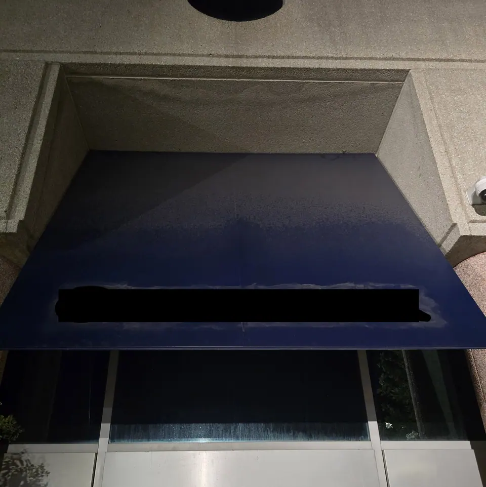 Blue commercial awning with visible surface buildup before cleaning.