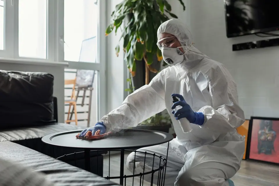 Worker wearing protective equipment cleaning a table.