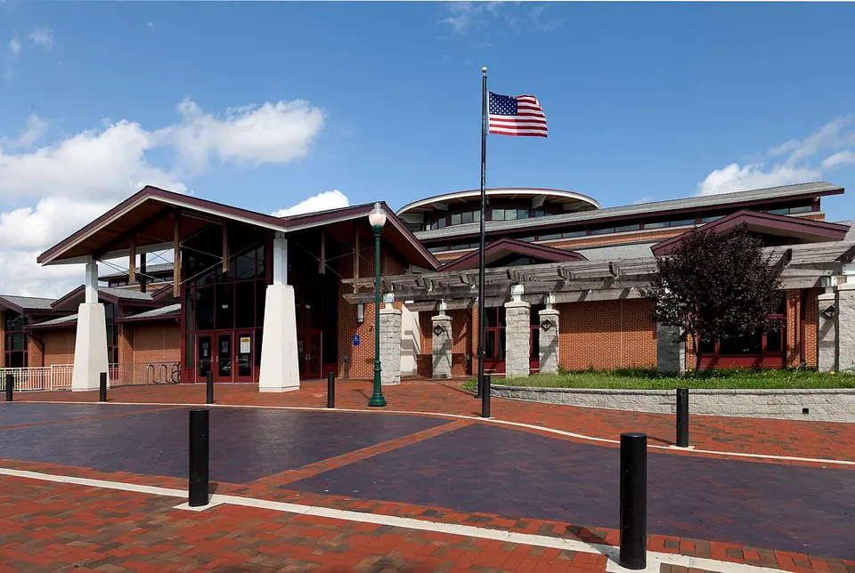 Brick-and-glass Germantown Library entrance with a paved plaza and American flag.